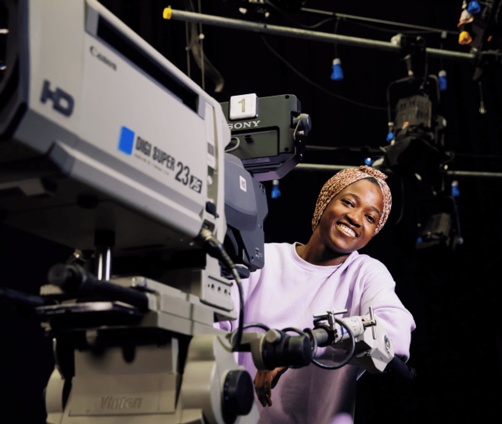 Female student with headscarf stands behind the  camera in the middlesex university tv studio