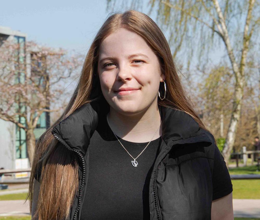 Abbi on campus on a sunny day with building in background