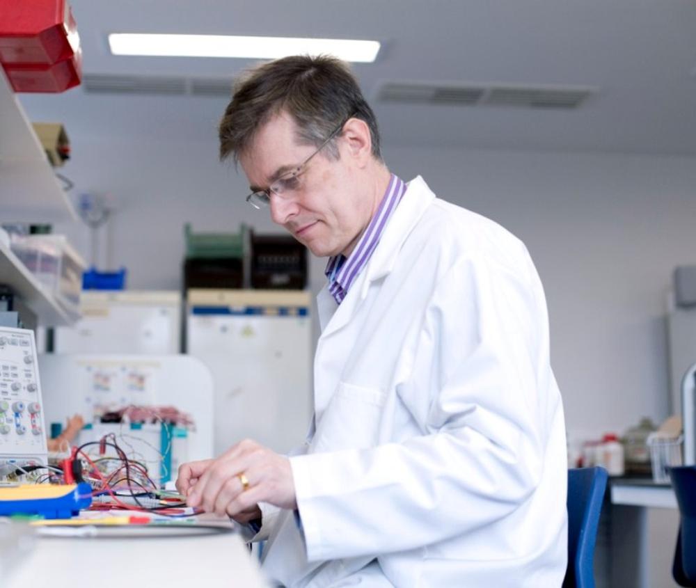 teacher in white lab coat examining something