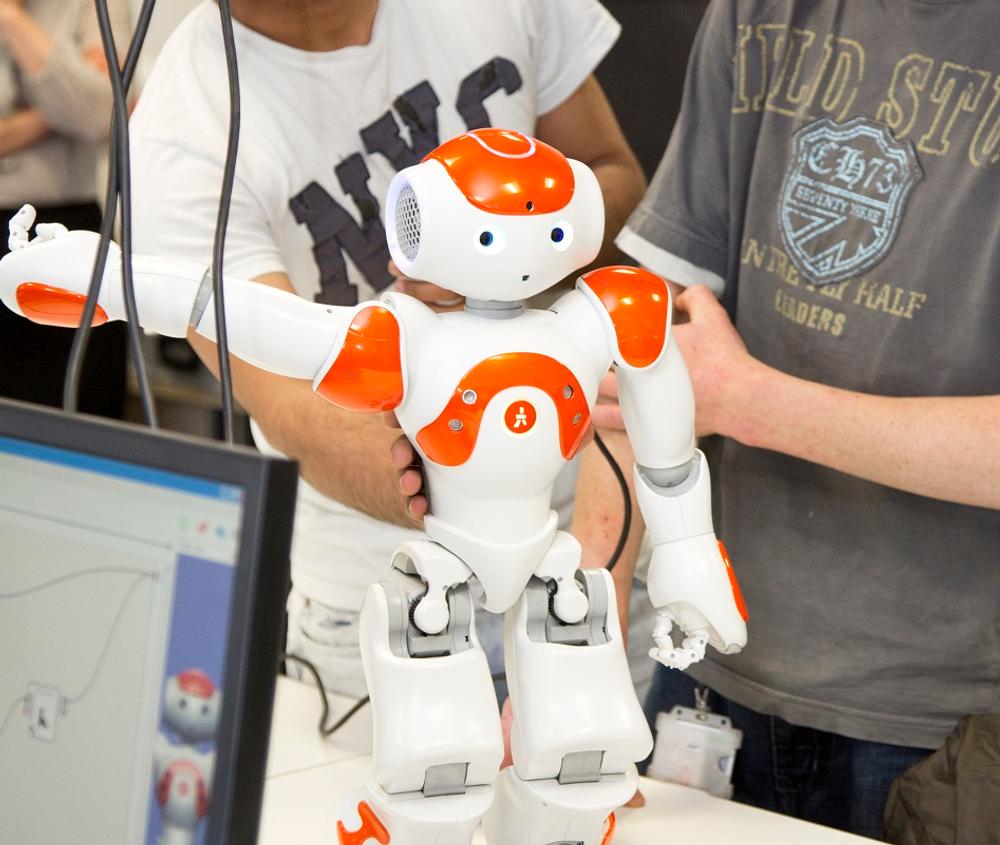 student holds small white robot