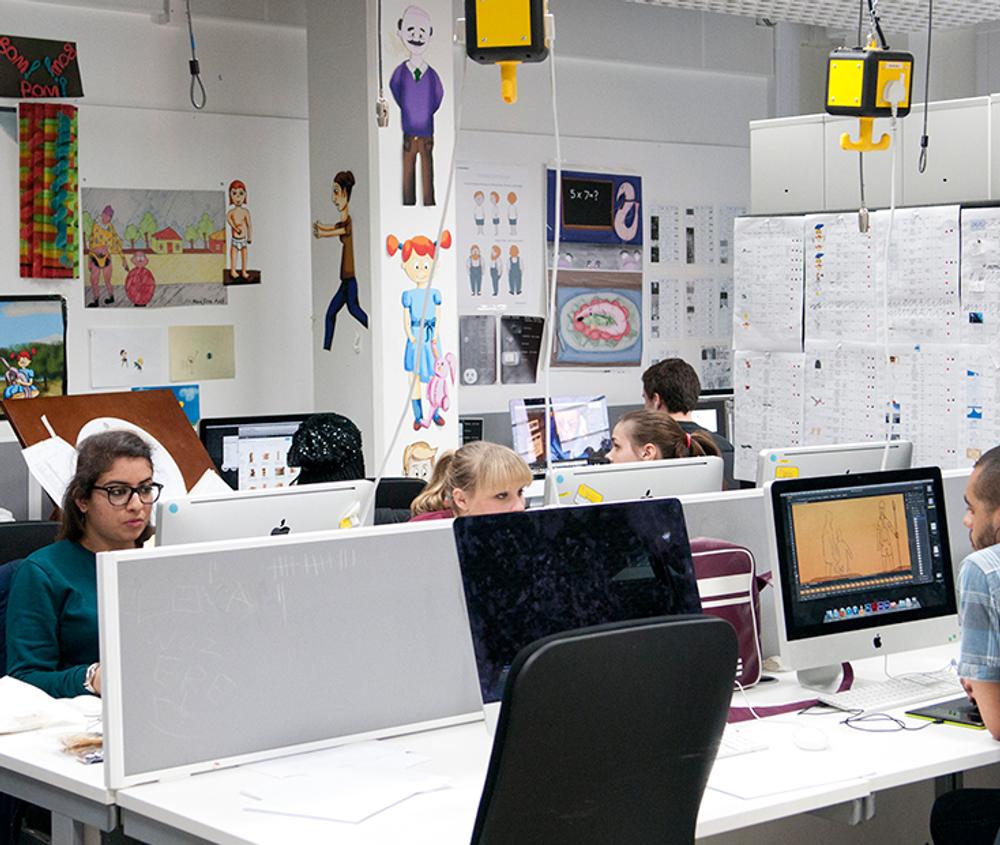 Students sitting at desks, looking at computer screens. The walls are covered in Animations and papers