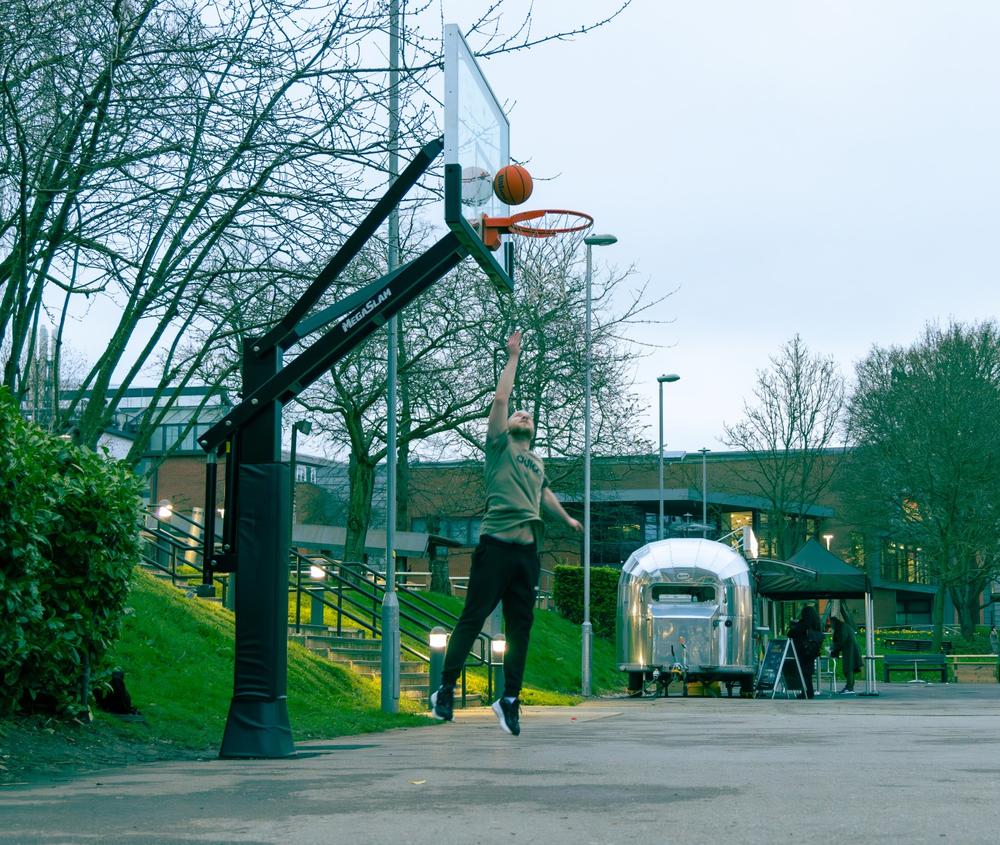 Student at Middlesex University shooting a basketball into a hoop.
