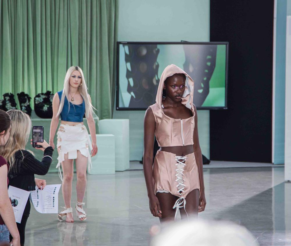 Two models walk along a catwalk in a student fashion show