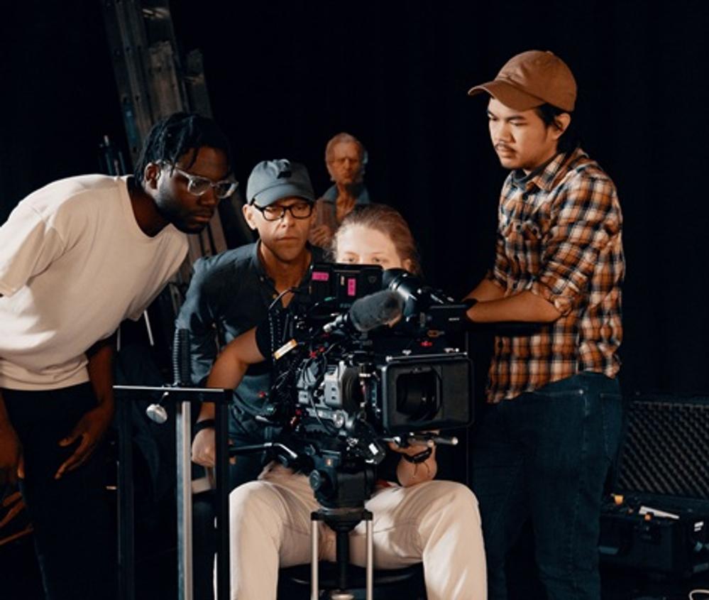 Students grouped around a camera on a film set