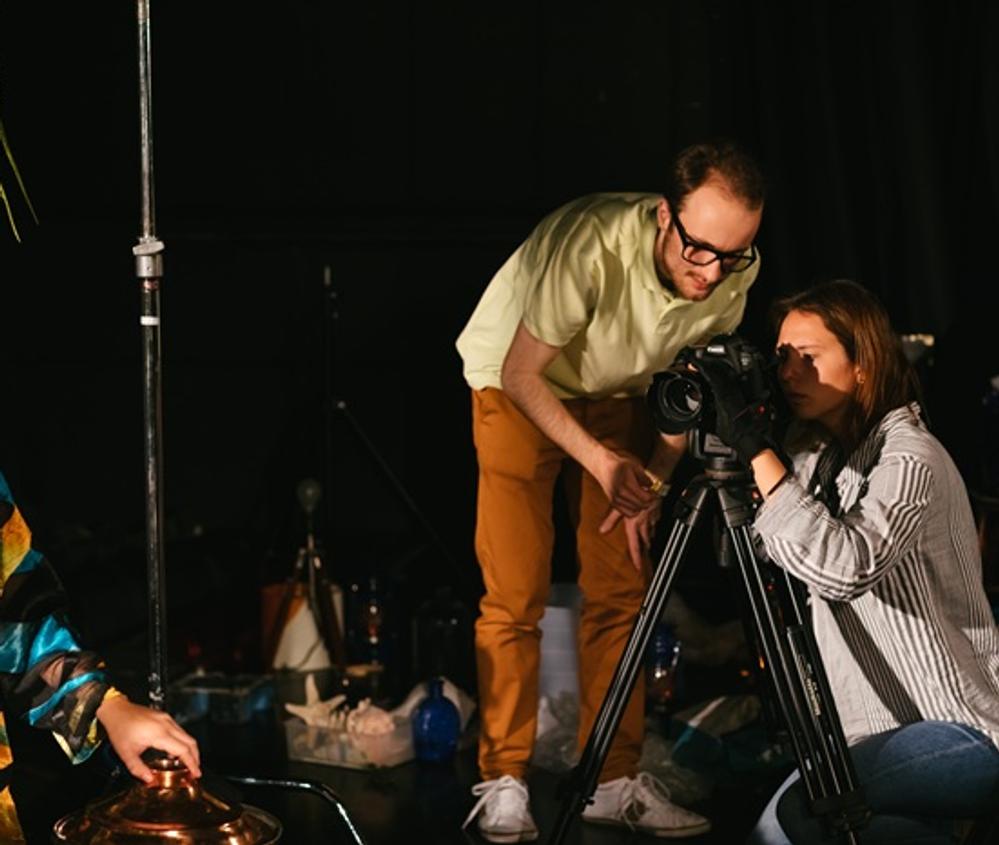 Two students examining a film camera on a dark film set