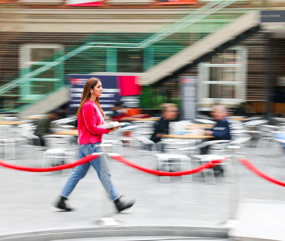 A student walks quickly through university quad building