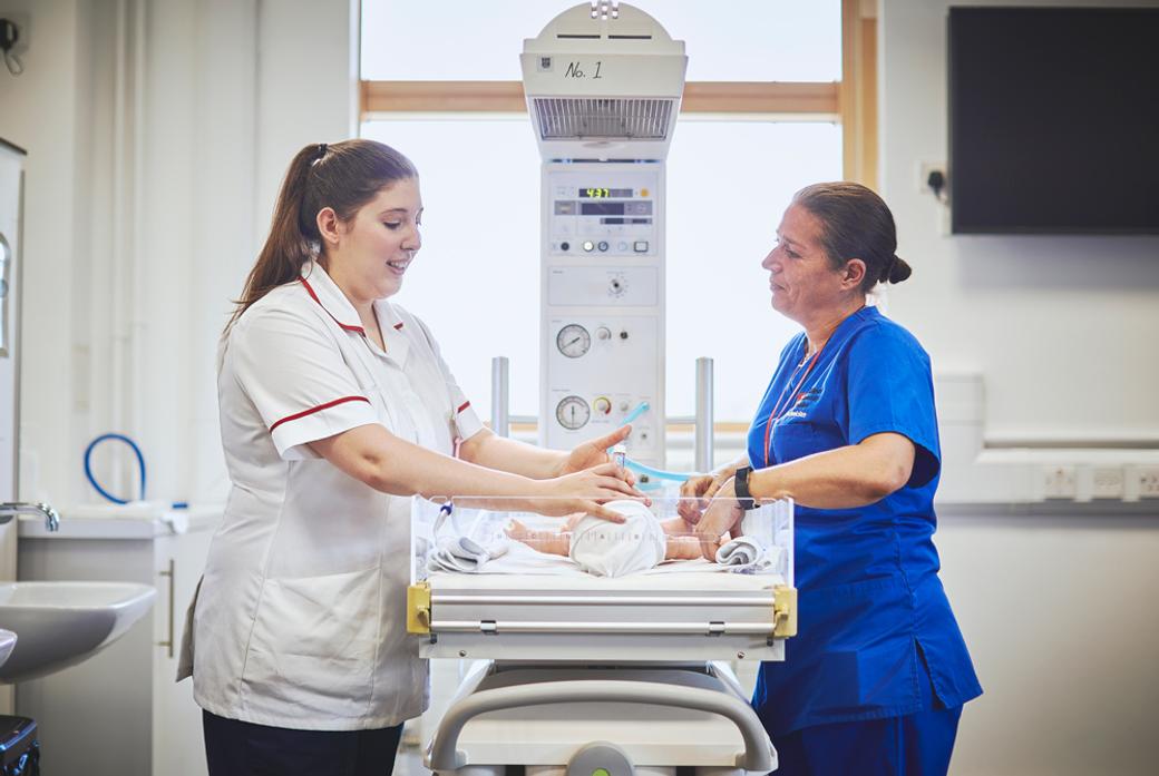 A nursing student and tutor in a hospital facility with a small baby