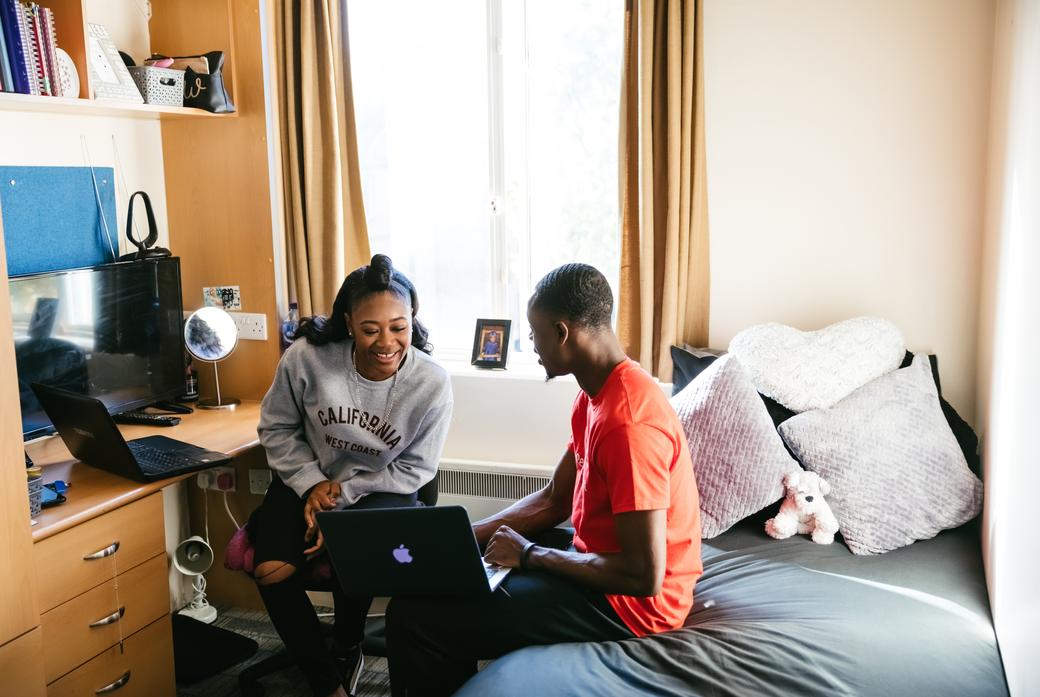 two students sit in bedroom studying together