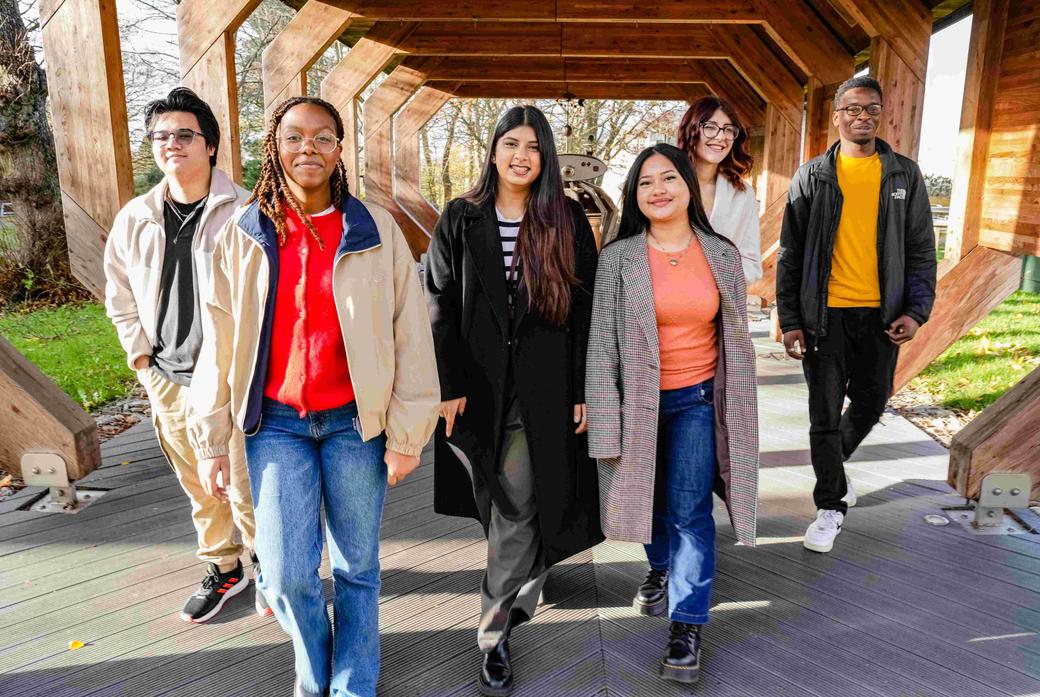Six students walking together under a wooden structure