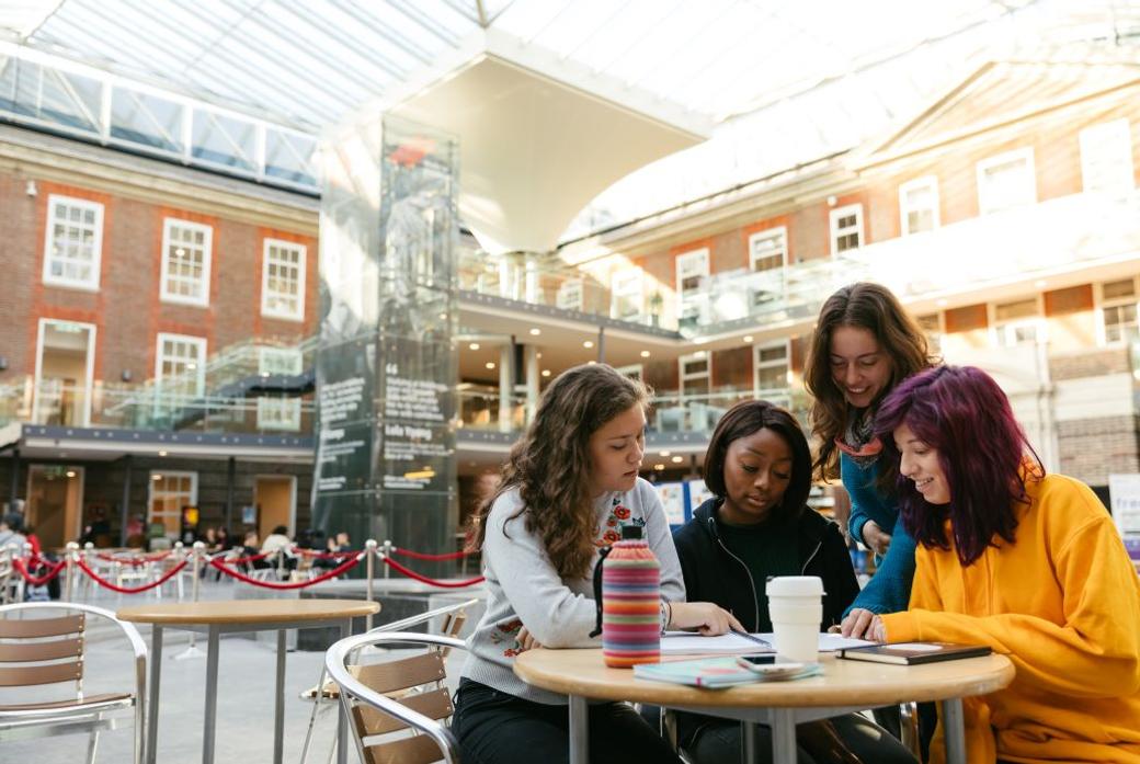 students sitting at a desk chatting with refreshments