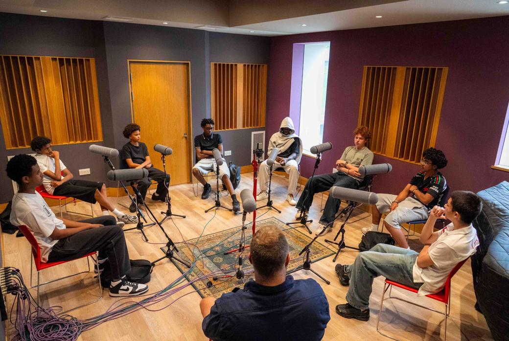 A group of male teenage students record a podcast as part of a project