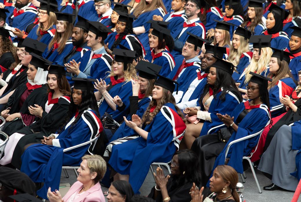 A crowd of graduating students sitting in their graduation robes and mortar boards