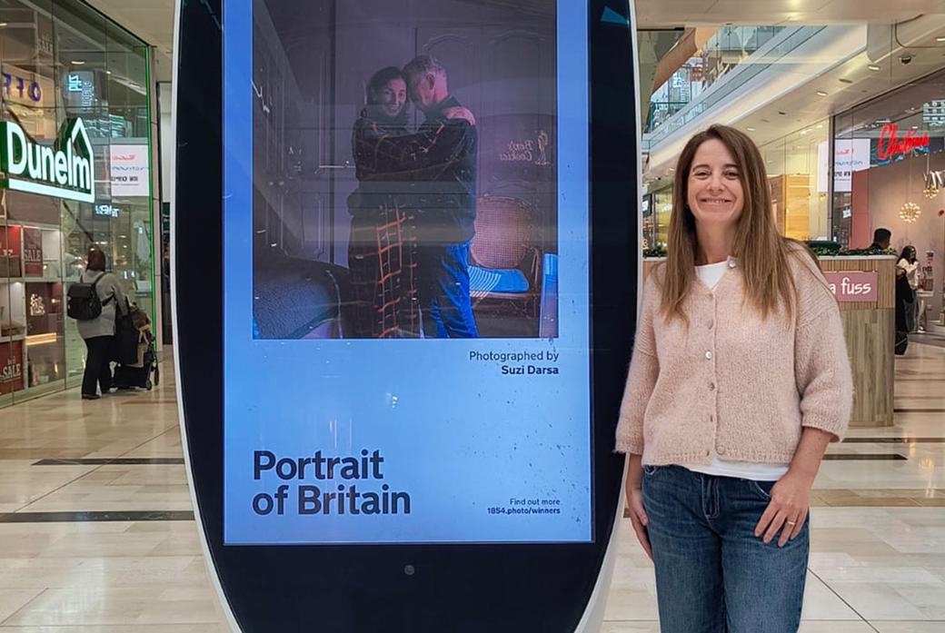 Woman stands next to billboard with image of couple