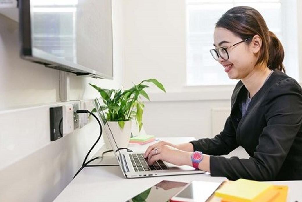 Female student sat at desk working on laptop