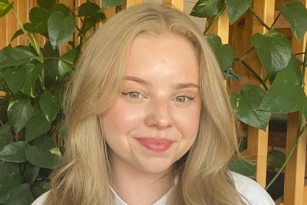 Wilma Claesson smiling while standing in front of a leafy plant