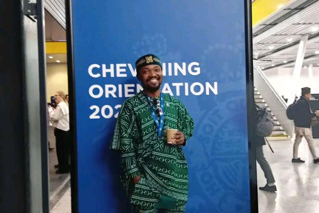 Student sitting with Chevening poster behind him