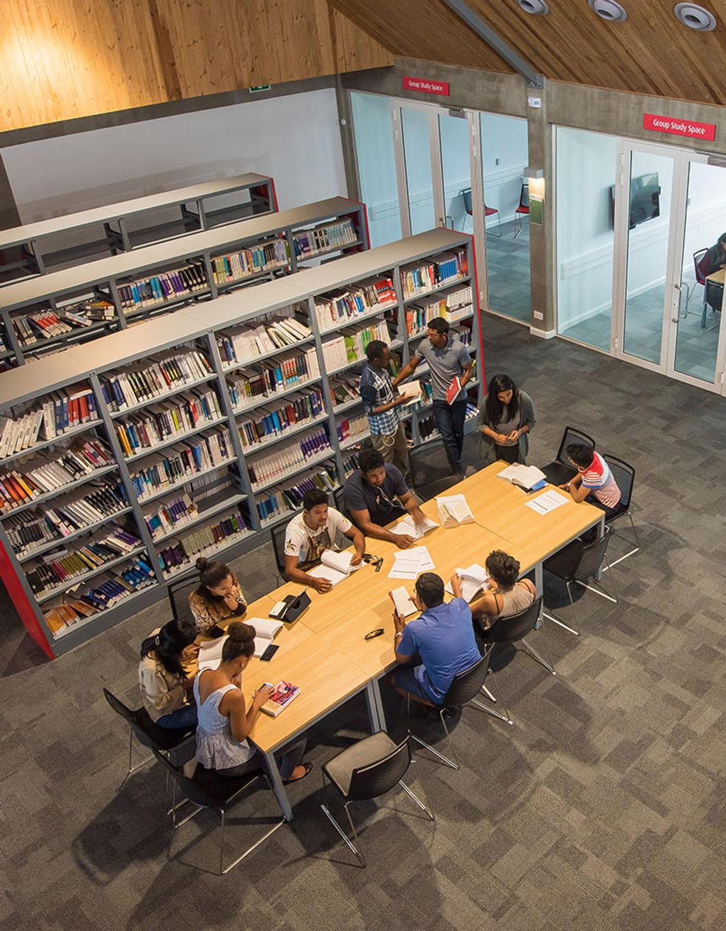 overhead shot of students working together at a large table in a library