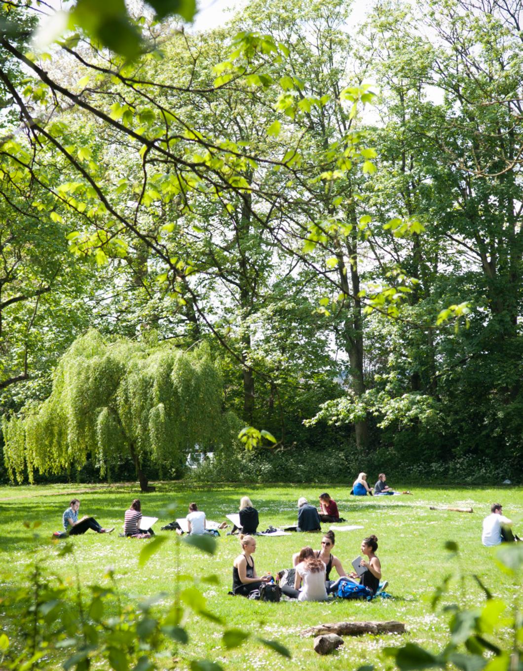 middlesex university students relaxing in the sunshine in the green spaces on campus in hendon