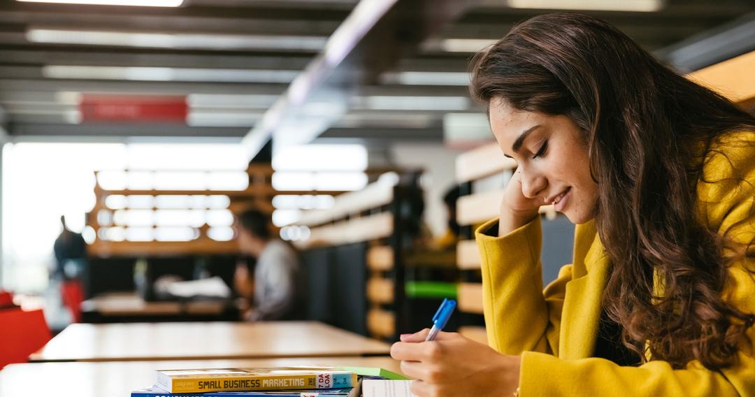 Young female student reading through business and economics books