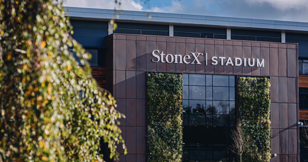 Large stadium exterior with grass and trees, stadium entrance says: Stone X Stadium