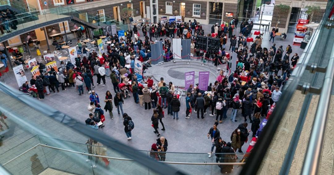 A diverse crowd of individuals gathered inside a spacious building, creating a vibrant and bustling atmosphere.