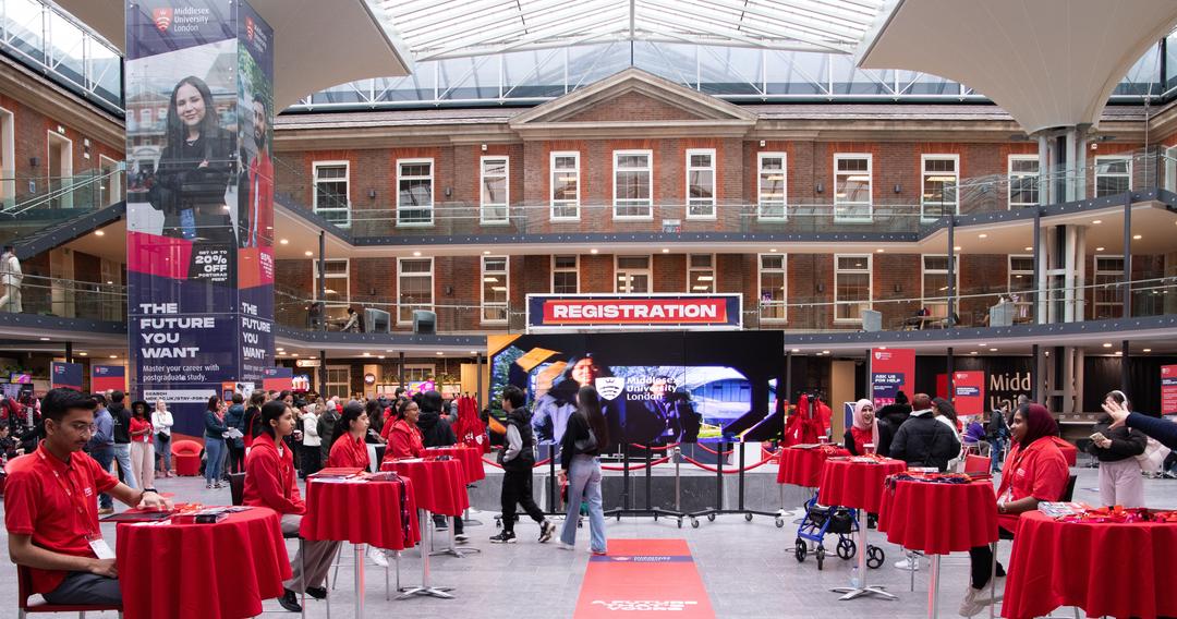 The Quad during an Open Day with two rows of tables with a person sat at each for visitors to register