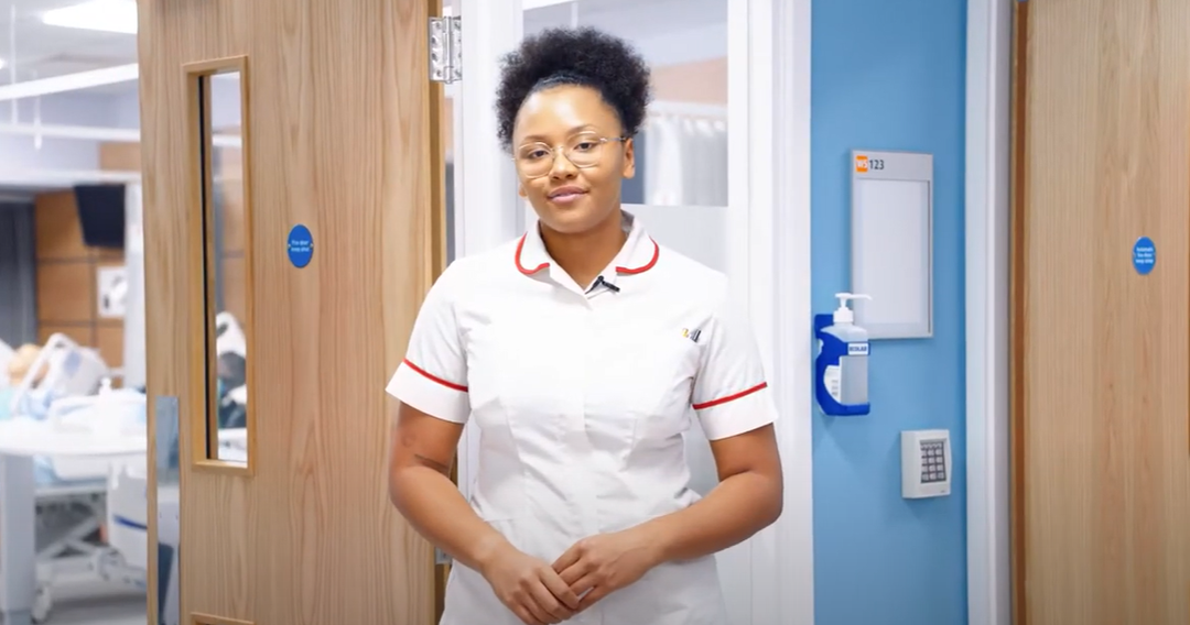 A nurse standing a hospital corridor talking in a video
