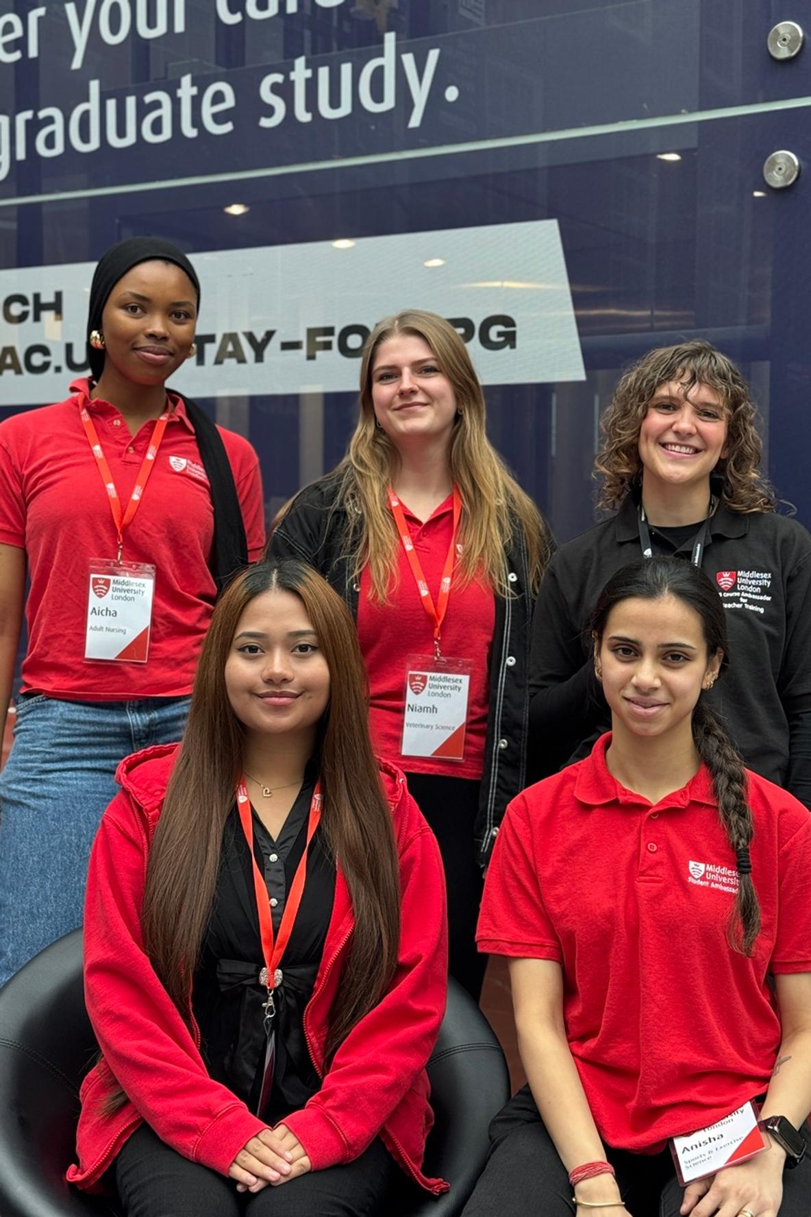 A group of five smiling people in branded open day tops