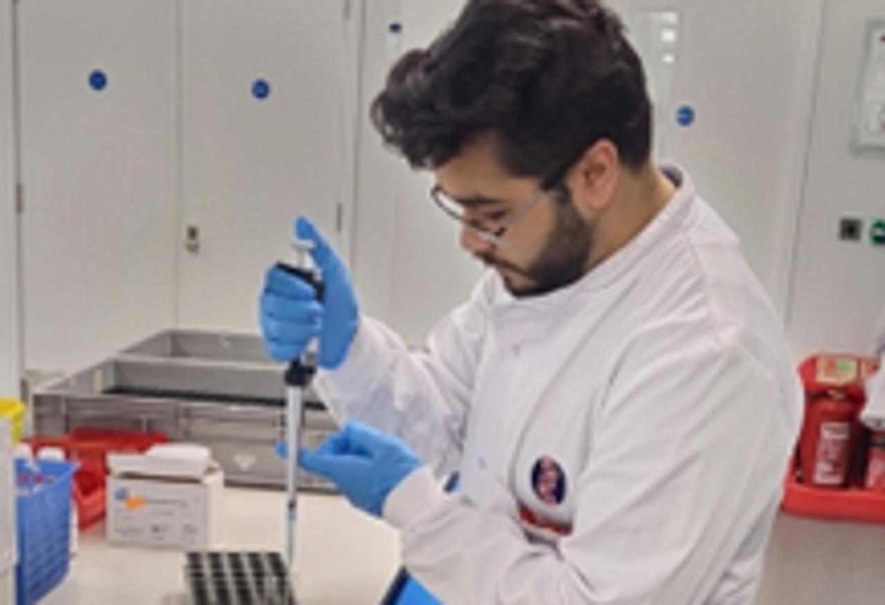Young student wearing a white coat filling in laboratory test tubes
