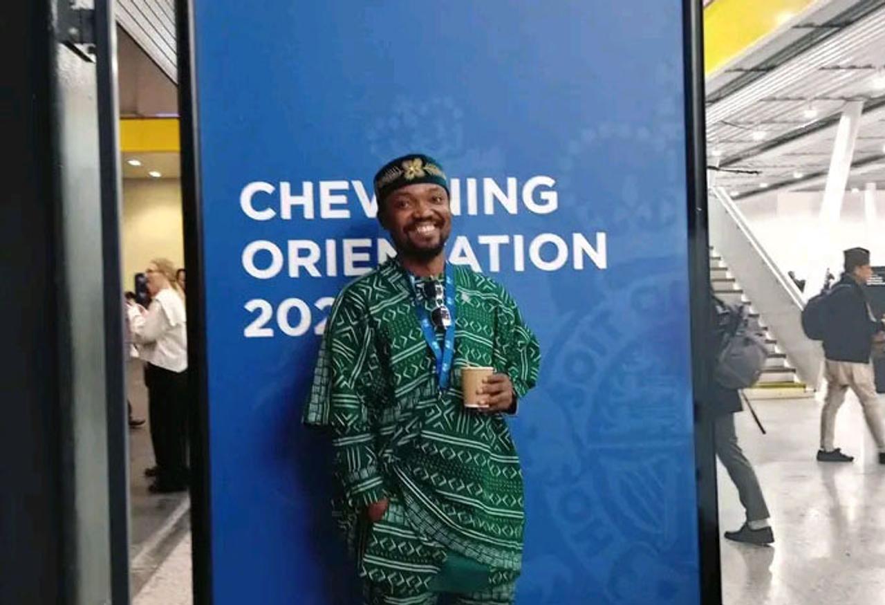 Student sitting with Chevening poster behind him