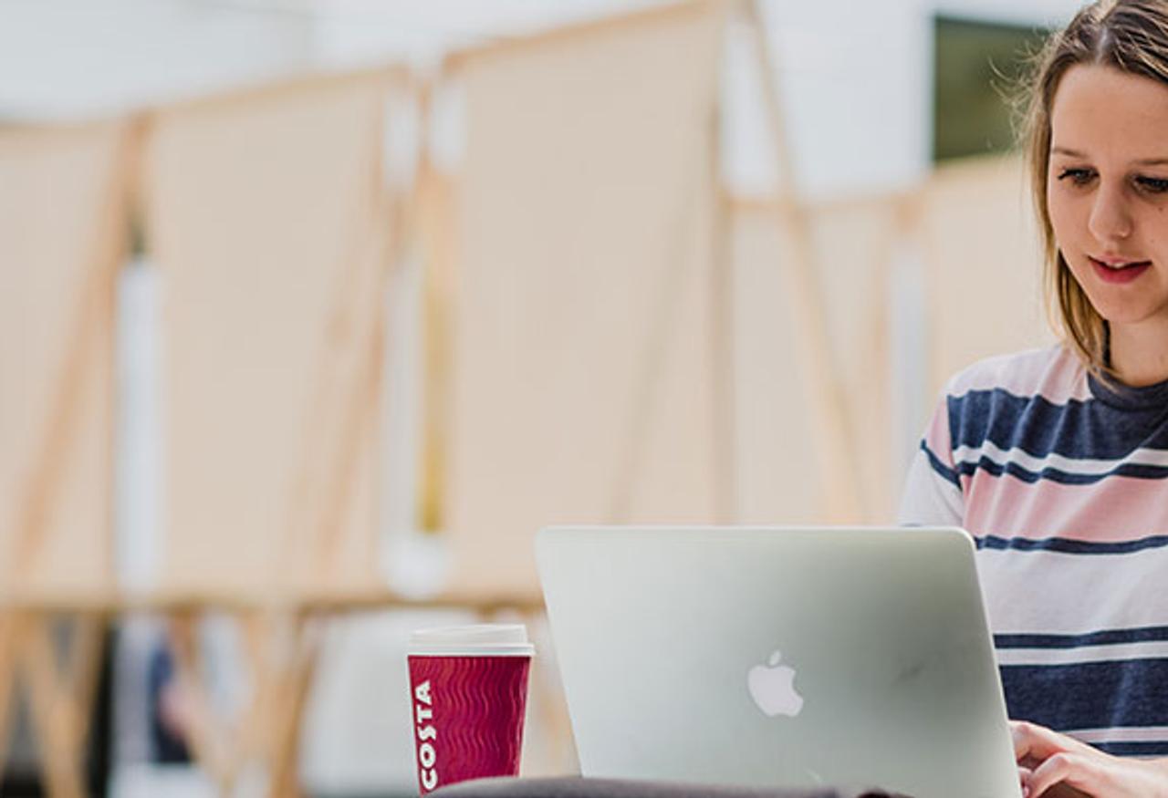 A woman sitting at a table with a laptop, focused on her work.