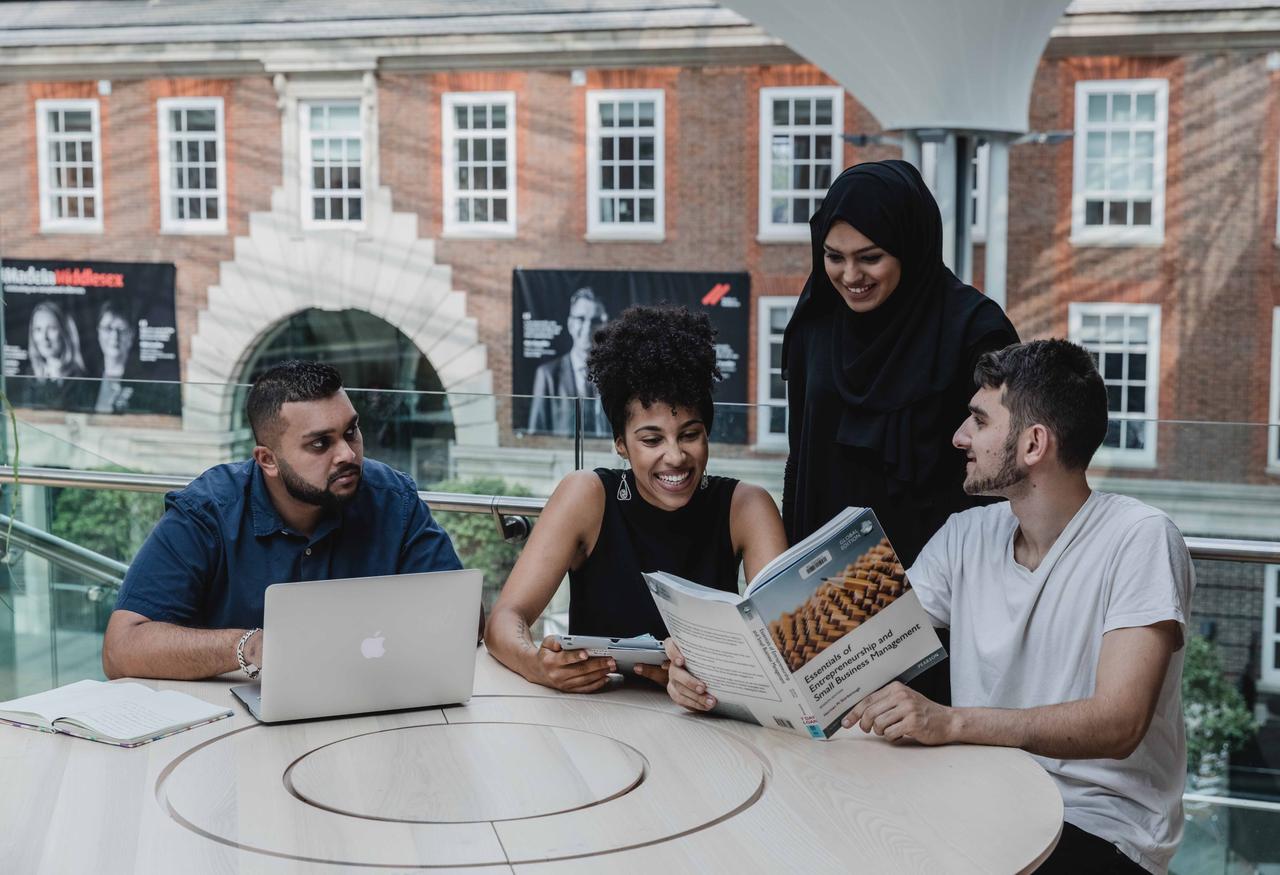 four business management students working together in the quad
