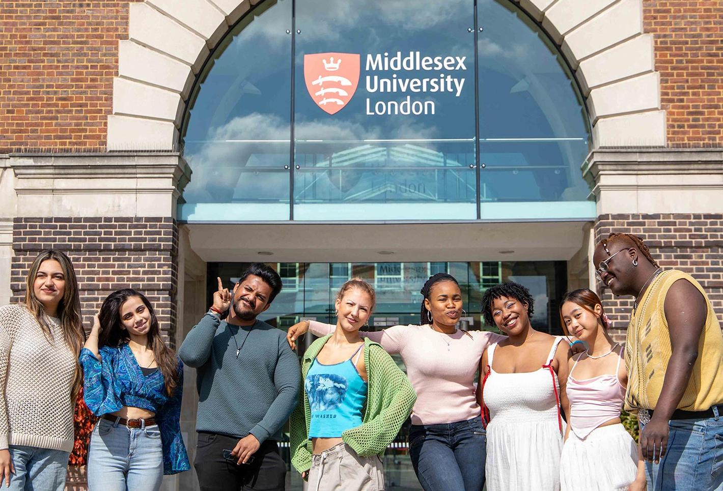 Students stood outside campus, with college building in the background.