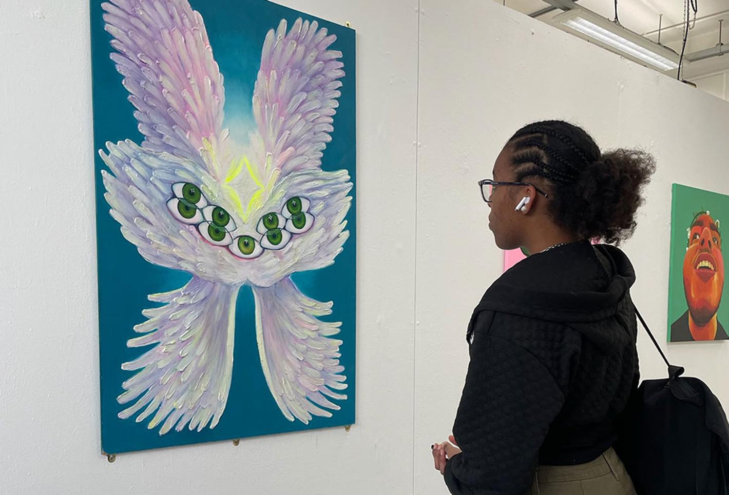 Female student stood looking at art on wall