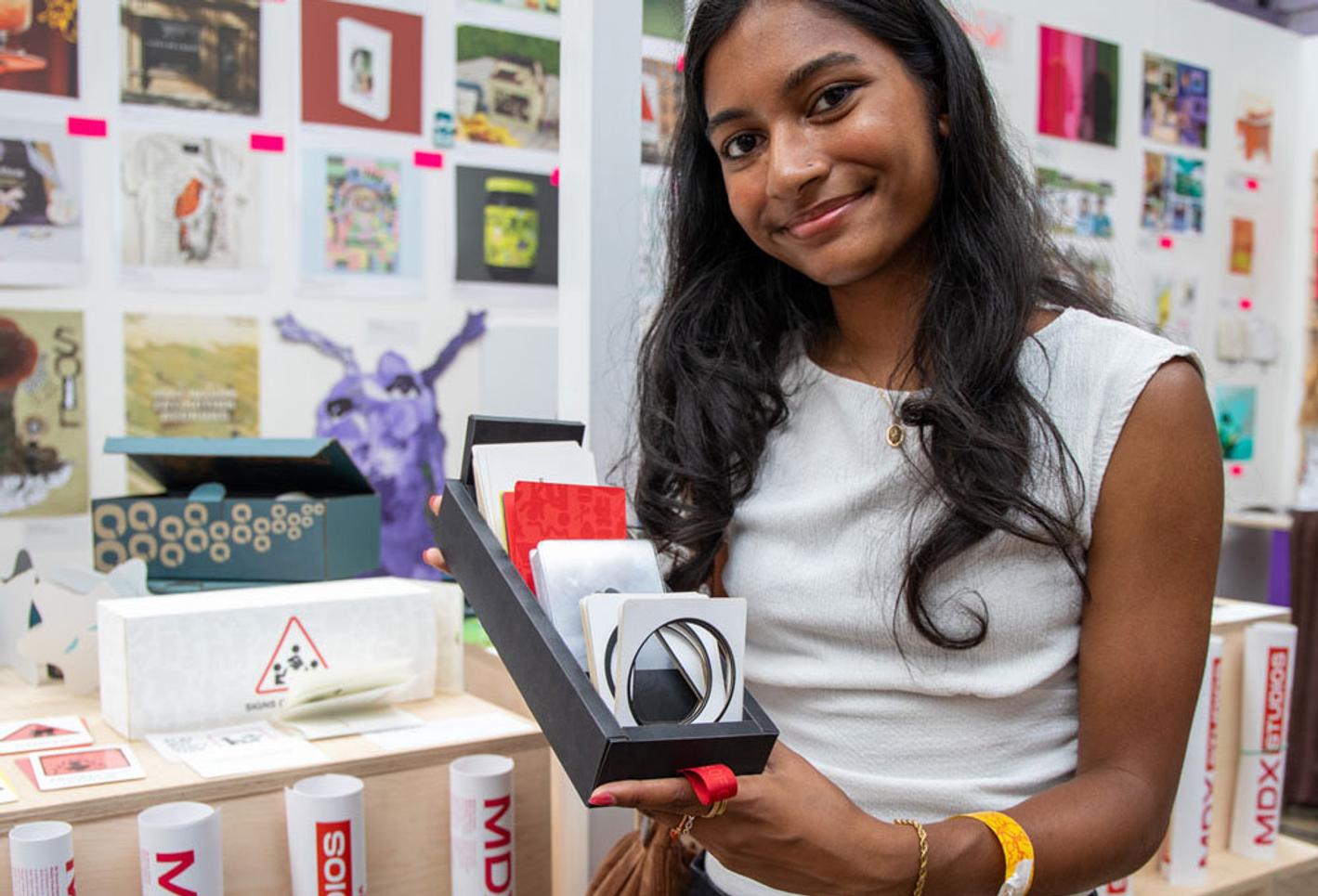 A female student holding up their work at a creative festival