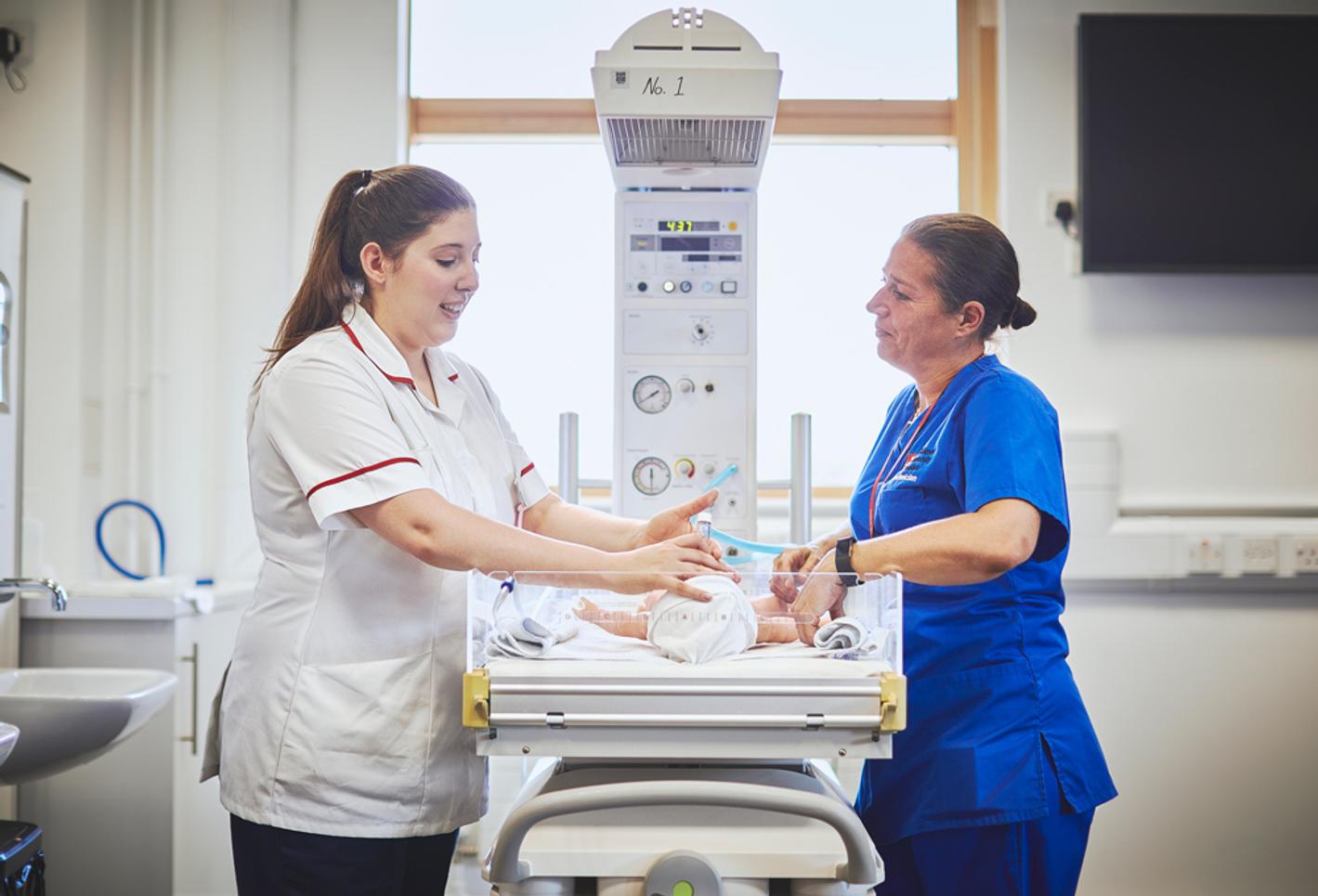 A nursing student and tutor in a hospital facility with a small baby