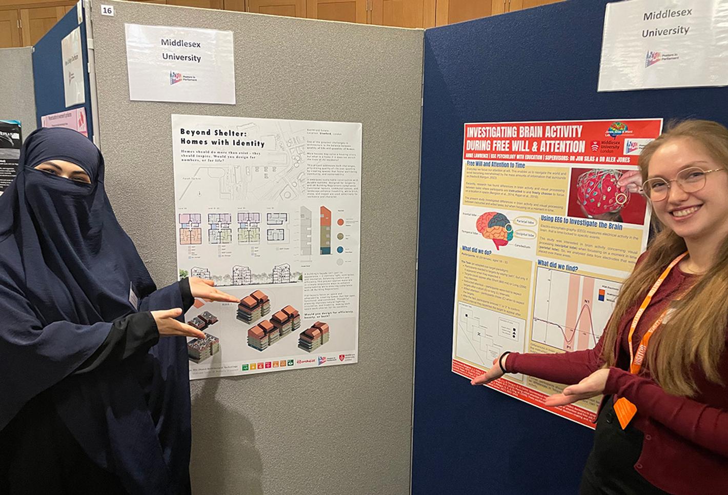 Two students stand either side of a display of posters