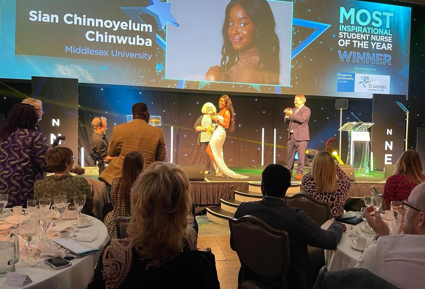 A student receiving her award at an awards ceremony, captivating the audience with her presence.