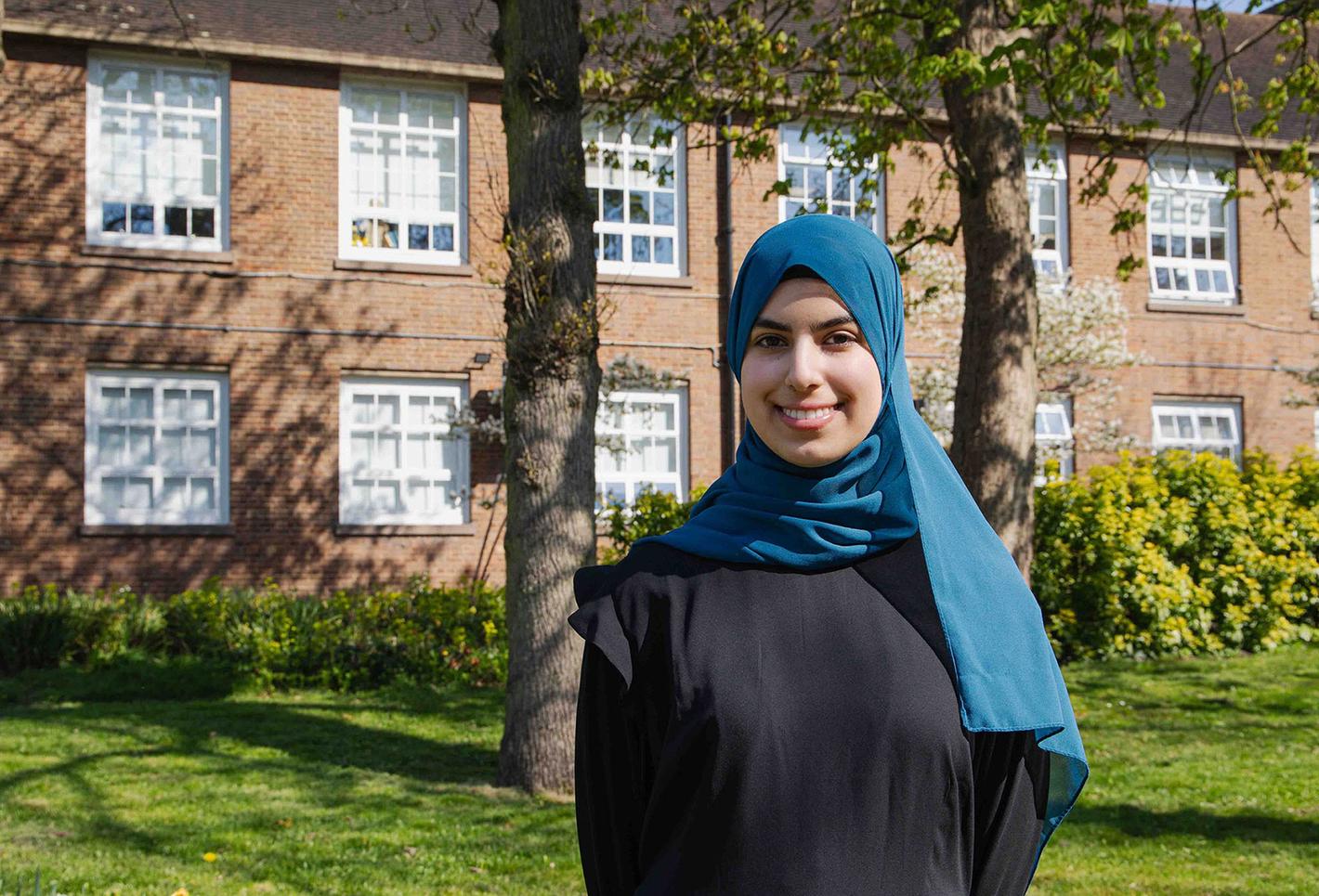 Student Duha posing in front of red bricked building