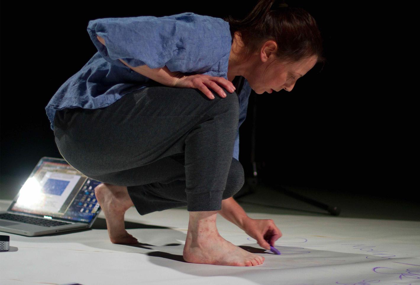 Artist in bare feet drawing on paper on the floor