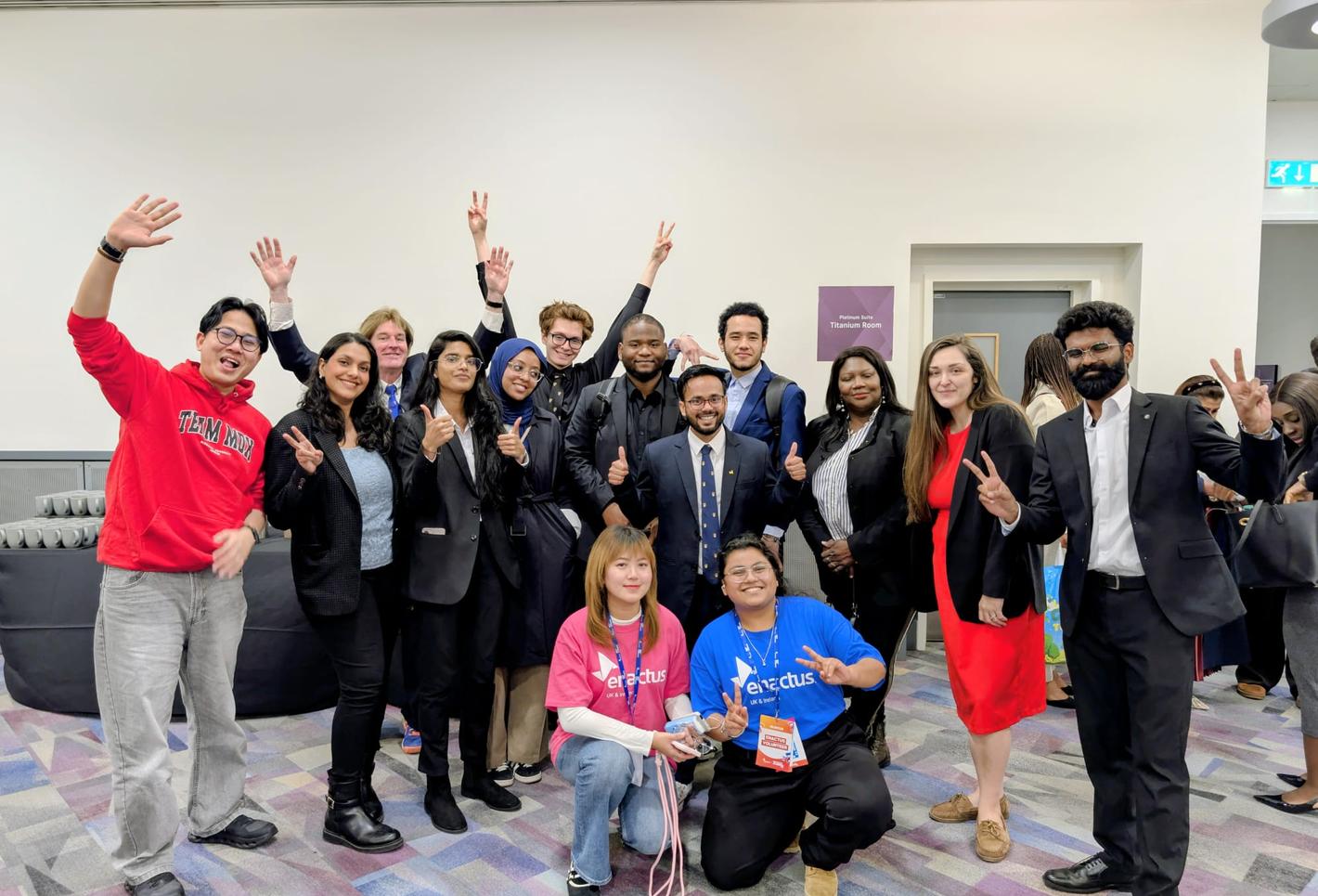 Group of Middlesex University students smiling and raising their hands at an Enactus event.