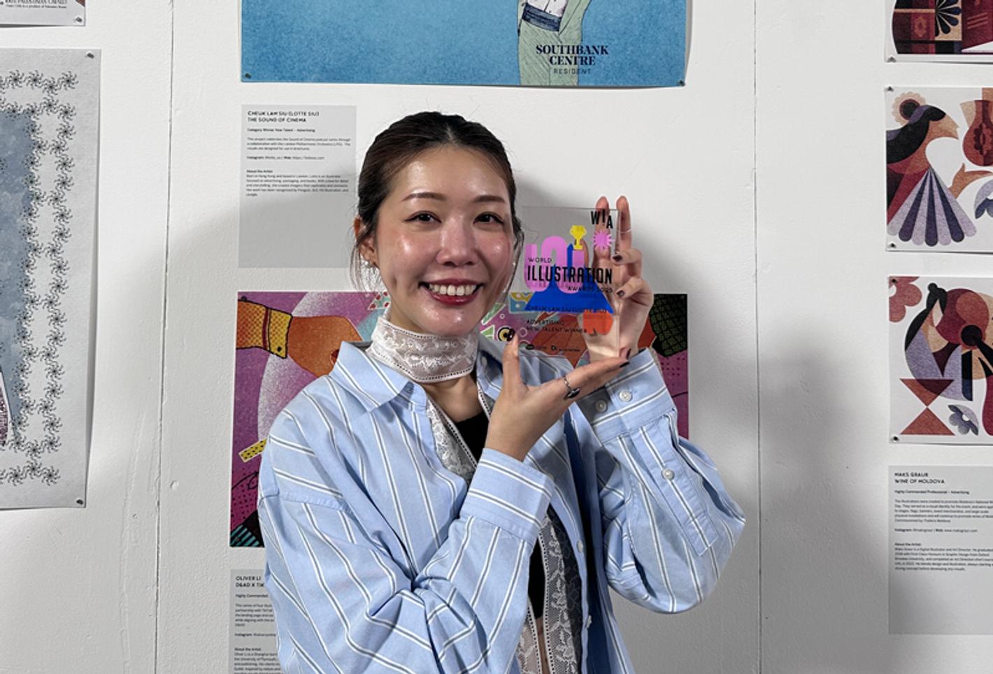 Middlesex University graduate Lotte Siu holds her award in front of a display of illustration