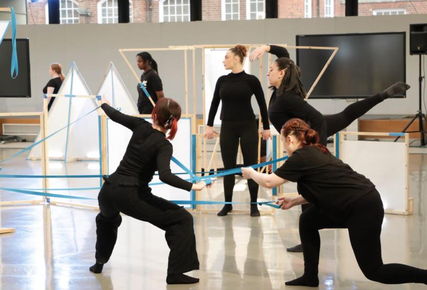 Group of dance students practise routine with stage props.