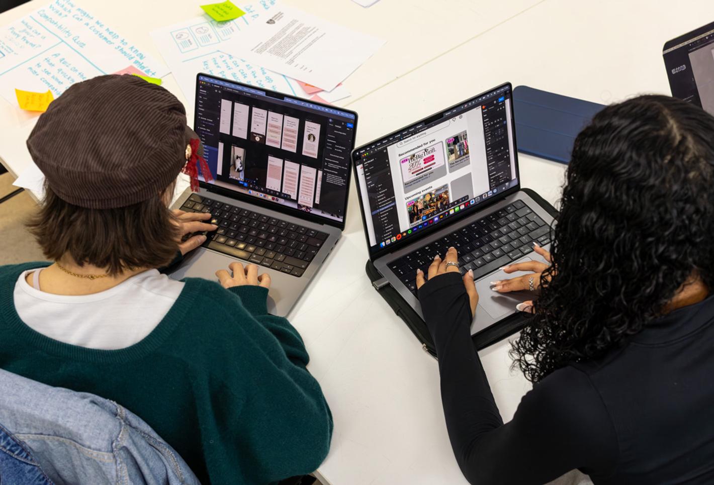 Two young people looking at laptop computers