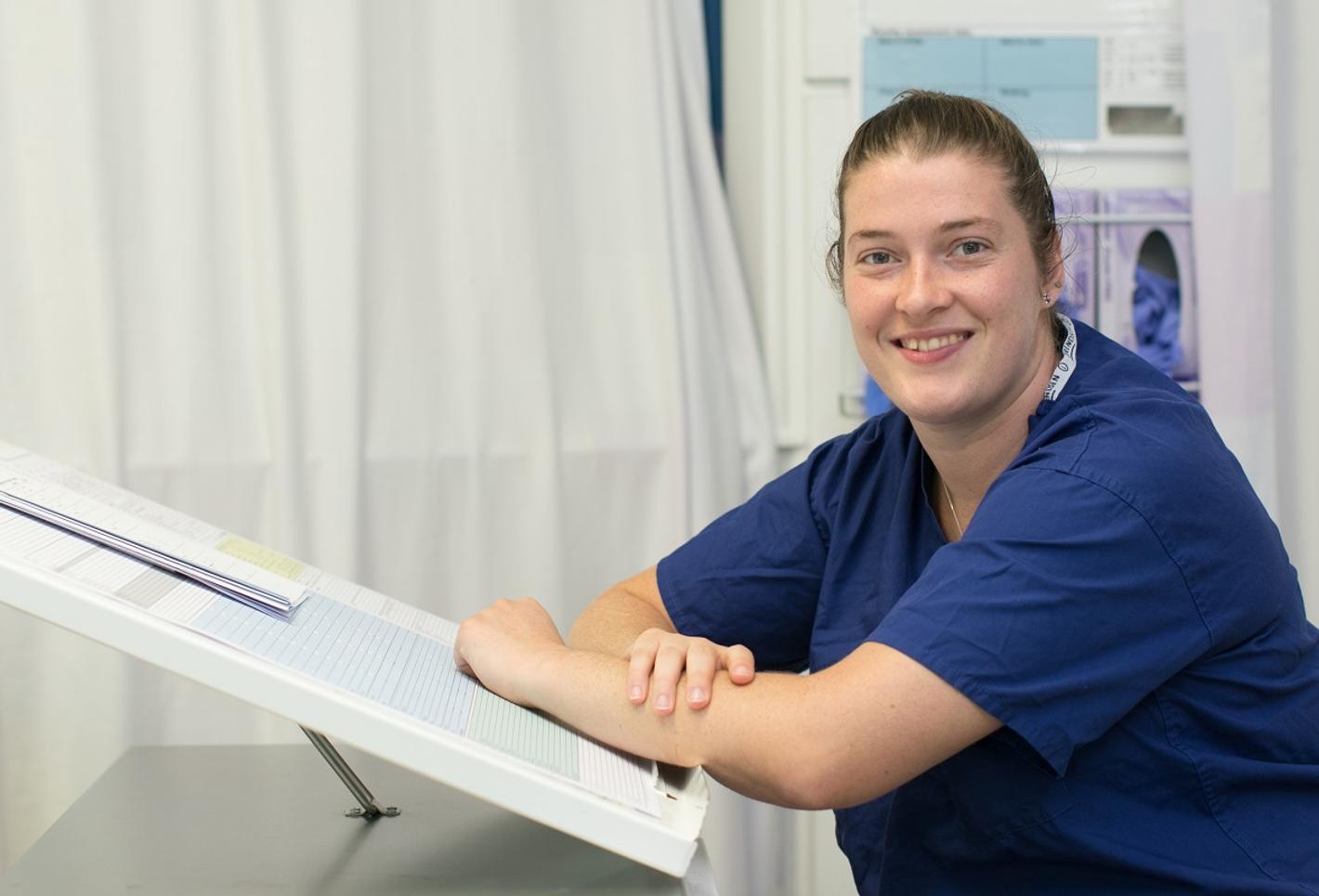 A female nurse sitting at a desk with a clipboard