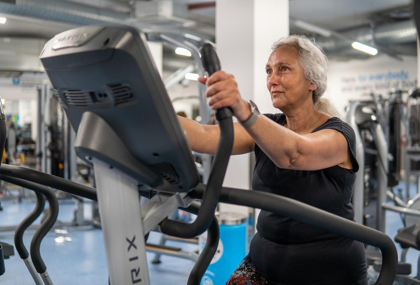 A woman is exercising on treadmill at gym