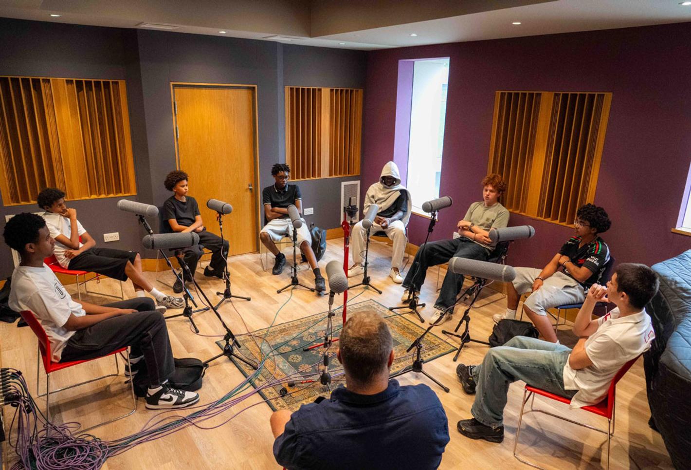 A group of male teenage students record a podcast as part of a project