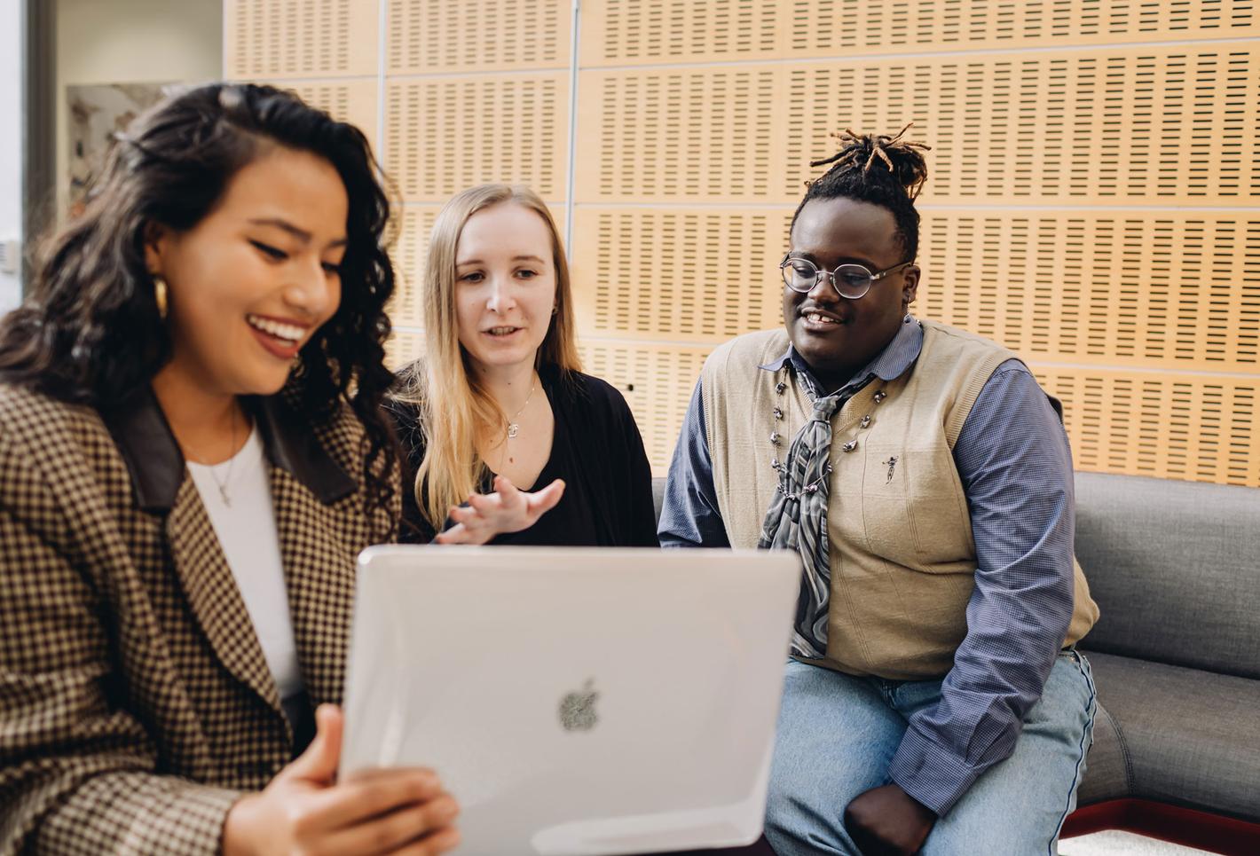 Mixed group of diverse people talking in front of a laptop.
