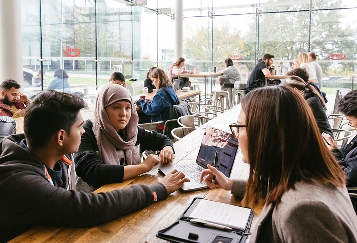 Students studying around a table in bright busy room