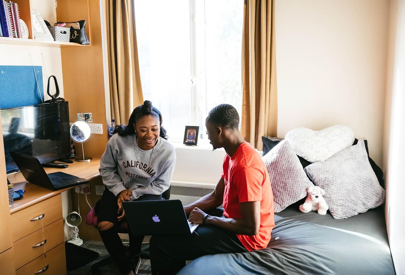 two students sit in bedroom studying together